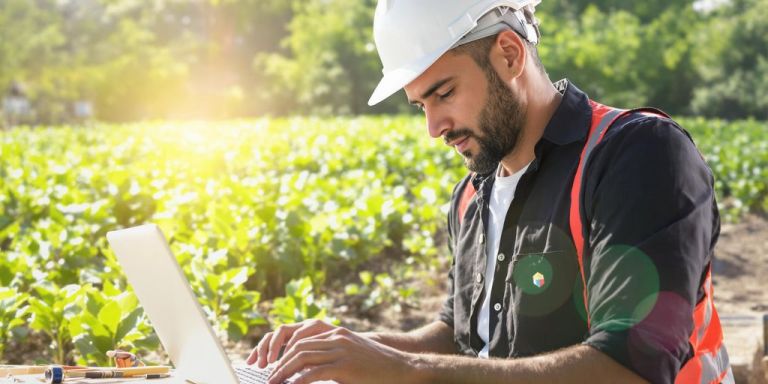Contractor using a laptop with a vibrant outdoor scene.