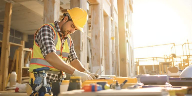 Contractor working on a sunlit construction site with tools.
